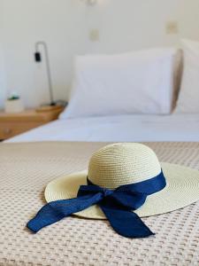 a straw hat with a blue ribbon sitting on a bed at Skopelos Inn in Stafylos