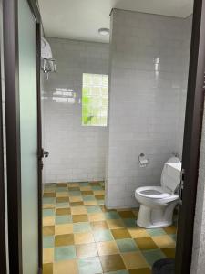 a bathroom with a toilet and a tiled floor at Graha Ayoe in Sidemen