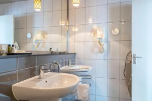 a bathroom with two sinks and two mirrors at Bouteaque Hotel in Maastricht