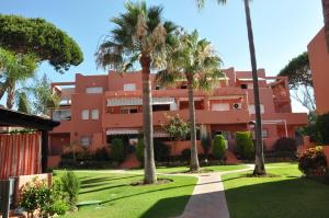 um edifício vermelho com palmeiras em frente em Apartment in Marbella em Marbella