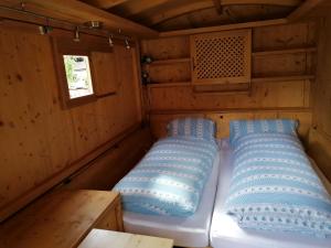 Una cama en una cabaña con almohadas azules. en Schlosswirt Chalets & Apartments, en Großkirchheim
