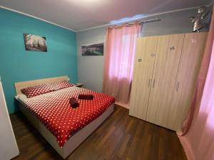 a bedroom with a bed with a red comforter and a cabinet at Guest House Devetaki in Devetaki