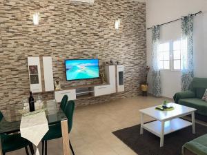 a living room with a tv and a brick wall at Casita 7 Islas in Giniginámar