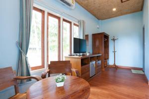 a living room with a wooden table and a television at Seafar Resort in Ko Kood