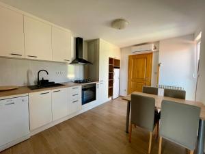 a kitchen with white cabinets and a table with chairs at Guest House Donatela in Valun +24 photos