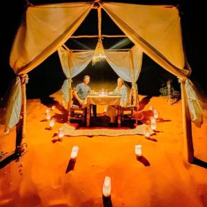 2 personnes assises à une table dans une tente dans l'établissement Blue Sky Luxury Camp, à Merzouga