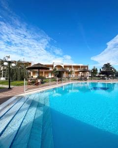 a large blue swimming pool in front of a building at Hotel Kalamitsi Apartments in Preveza