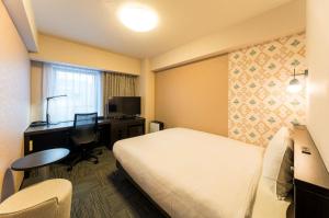 a hotel room with a bed and a desk and a computer at Richmond Hotel Aomori in Aomori