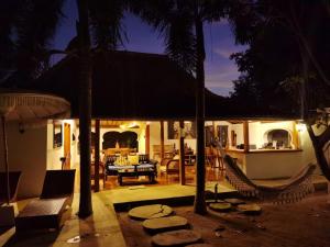 un patio con hamacas y una casa por la noche en Ardi Beltza Hotel and Private Pool Villa en Gili Air
