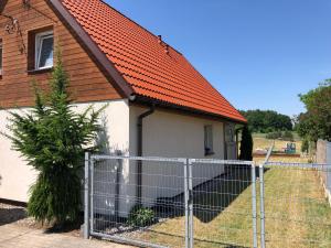 Warpuny的住宿－Domek na Mazurach Apartamenty nad jeziorem Warpuny，一座带橙色屋顶和围栏的小房子