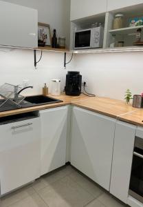 eine Küche mit weißen Schränken und einem Waschbecken in der Unterkunft Cosy and Spacious appartement near metro line 4 & RER B in Bagneux