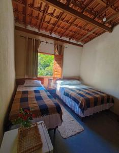 Cette chambre comprend 2 lits et une fenêtre. dans l'établissement Reserva do Bosque Hospedaria e Natureza, à Ibicoara