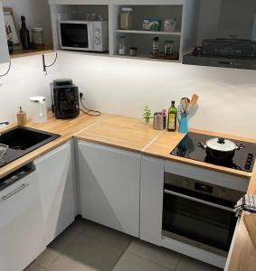 a kitchen with white cabinets and a wooden counter top at Cosy and Spacious appartement near metro line 4 & RER B in Bagneux