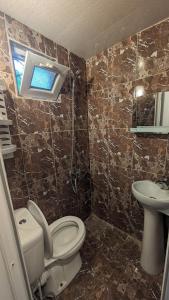 ein Bad mit einem WC, einem Waschbecken und einem Fenster in der Unterkunft Guest House NINI in Bordschomi