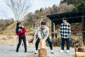 un gruppo di tre persone che giocano con un tronco d'albero di サウナ付き古民家宿まるもり a Wada