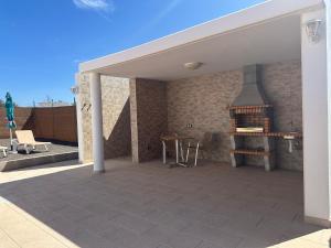 a covered patio with a table and a fireplace at Casita 7 Islas in Giniginámar