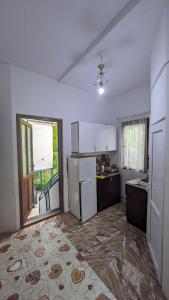 eine Küche mit weißen Geräten und einem großen Fenster in der Unterkunft Guest House NINI in Bordschomi