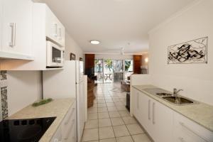 a kitchen with white cabinets and a sink at On Palm Cove Beachfront Apartments in Palm Cove