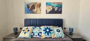 a bedroom with a blue bed with three pictures on the wall at Sea Breeze Penthouse and Terrace Qawra St Paul's Bay in St Paul's Bay