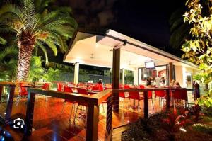 a restaurant with red tables and chairs and a palm tree at BEST Ground Floor pool side Superior apartment - new listing in Gold Coast
