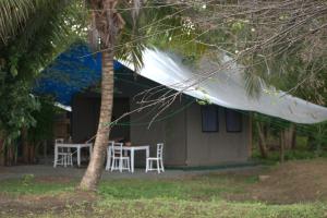 ein Haus mit einem Tisch, Stühlen und einem Zelt in der Unterkunft Harmony Haven Eco Camp, Udawalawa in Udawalawe
