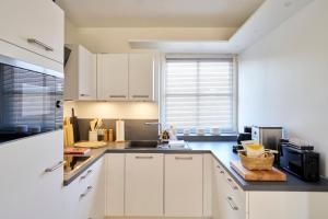una cocina con armarios blancos y fregadero en Haus am Nordstrand, en Norderney