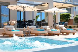 a pool with couches and umbrellas in a building at Minoas Villas Heated Pool in Kournás