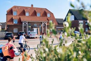 un gruppo di persone che vanno in bicicletta davanti a una casa di Haus am Nordstrand a Norderney