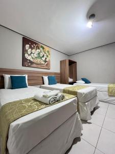 una camera d'albergo con tre letti di Hotel Cantinho Verde a Teixeira de Freitas