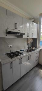 eine Küche mit weißen Schränken und einem Kochfeld in der Unterkunft Городской эдем: уют и комфорт in Yerevan