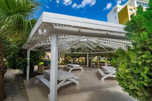 Una pérgola blanca con mesas de picnic y bancos. en Seaview stylish one bedroom apartment in Caesar Resort, Remus 83, en Perivolia tou Trikomou