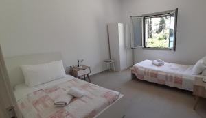 a white bedroom with two beds and a window at Villa Elsi upper apartment in Kalami