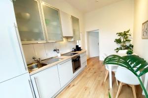 メンヒェングラートバッハにあるModernes City-Apartment in Mönchengladbachの白いキャビネットと植物が置かれたテーブルのあるキッチン