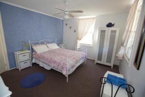 a bedroom with a bed and a ceiling fan at Bush & Bay Cottage in Erowal Bay