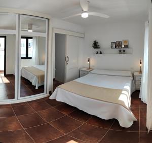 ein Schlafzimmer mit einem großen weißen Bett und einem Spiegel in der Unterkunft Casa Remo in Playa Honda