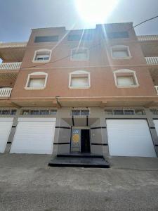 a building with four white garage doors on it at Appartement à Houma, proche Port Tanger Med in Dalia