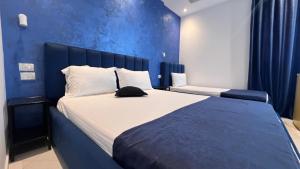 - une chambre avec un grand lit et un mur bleu dans l'établissement Hotel RivierA, à Durrës