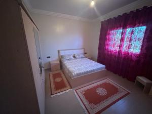 a small bedroom with a bed and red curtains at Appartement à Houma, proche Port Tanger Med in Dalia