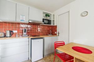 モントルイユにあるTop Appartement avec Wifi - Proche Paris & Métro - R6のキッチン(白いキャビネット、木製テーブル、赤い椅子付) +3枚の写真