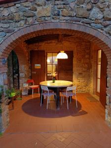 a patio with a table and chairs in a stone wall at Il Casolare del Pastore in Suvereto