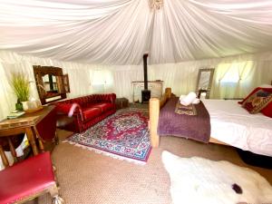 a bedroom with a tent with a bed and a couch at Elessar Yurt Village in Chichester