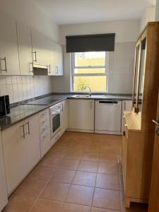 a kitchen with white cabinets and a tile floor at Porto Santo Happy Place in Porto Santo +15 photos