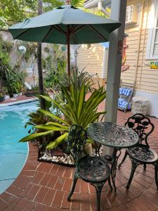 a table and chairs with an umbrella next to a pool at The Garden House in Key West