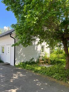 una casa bianca con un albero davanti di Egen lägenhet i charmig miljö i Linköping V a Vikingstad