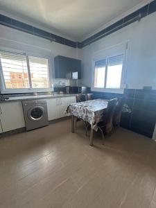 a kitchen with a table and a washing machine at Appartement à Houma, proche Port Tanger Med in Dalia