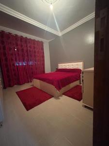 a bedroom with a bed and two red rugs at Appartement à Houma, proche Port Tanger Med in Dalia