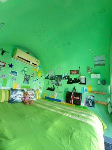 ein Zimmer mit einer grünen Wand mit einem Bett und einer Person in der Unterkunft 與大自然融合的包棟小屋 in Altstadt von Hengchun