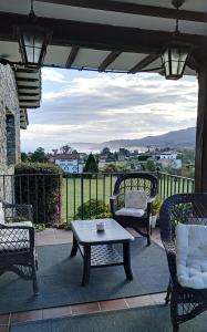 a patio with chairs and a table and a view of a town at Hotel Los Caspios in Colunga