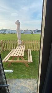 a picnic table with an umbrella next to a fence at All Seasons Chalet Breaks in Leysdown-on-Sea