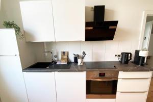 a kitchen with white cabinets and a sink at Modernes City-Apartment in Mönchengladbach in Mönchengladbach